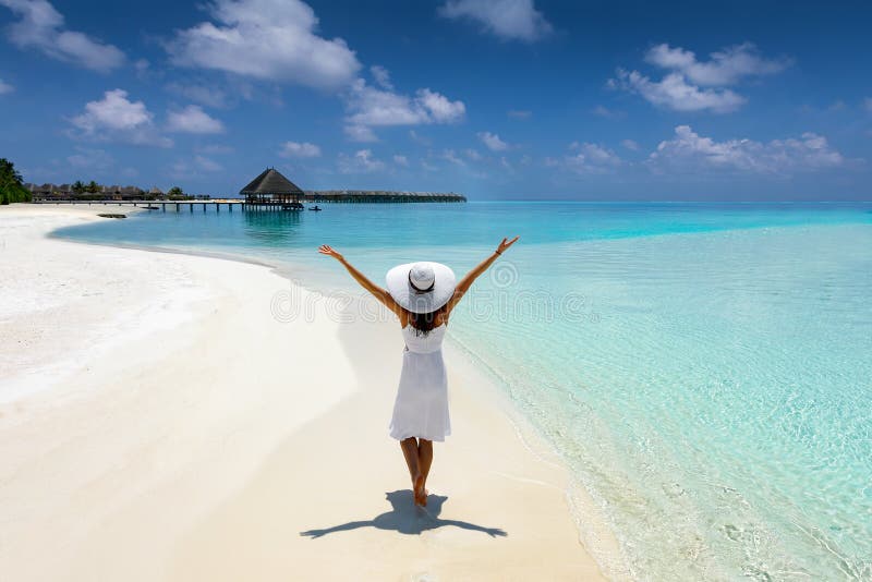 Elegante Frau im Weiß geht auf einen tropischen Strand in den Malediven lizenzfreies stockbild Elegante Frau im Weiß geht auf einen tropischen Strand in den Malediven lizenzfreies stockbild
