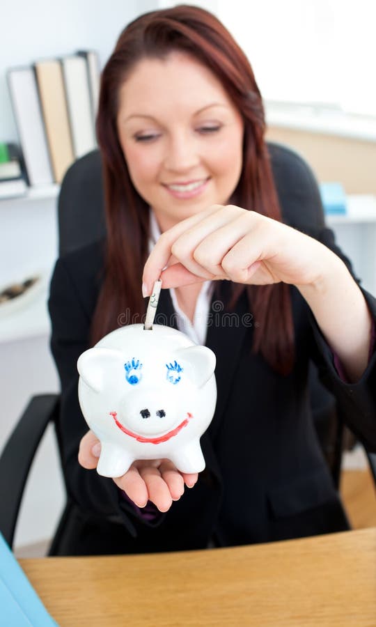 Elegante Geschäftsfrau, die Geld in ein piggybank einsetzt lizenzfreies stockbild Elegante Geschäftsfrau, die Geld in ein piggybank einsetzt lizenzfreies stockbild