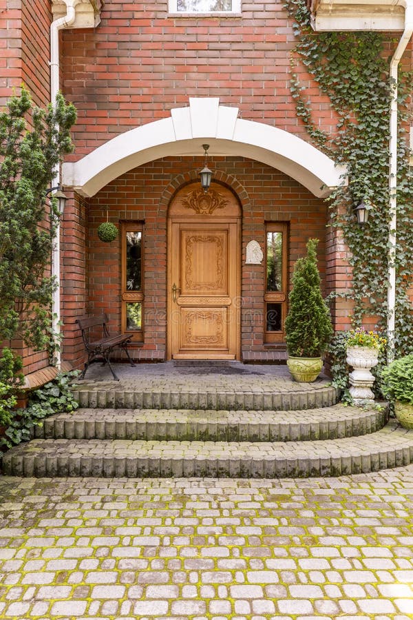 Elegante, houten ingangsdeur aan een landgoed met klimop het groeien op B stock afbeeldingen Elegante, houten ingangsdeur aan een landgoed met klimop het groeien op B stock afbeeldingen