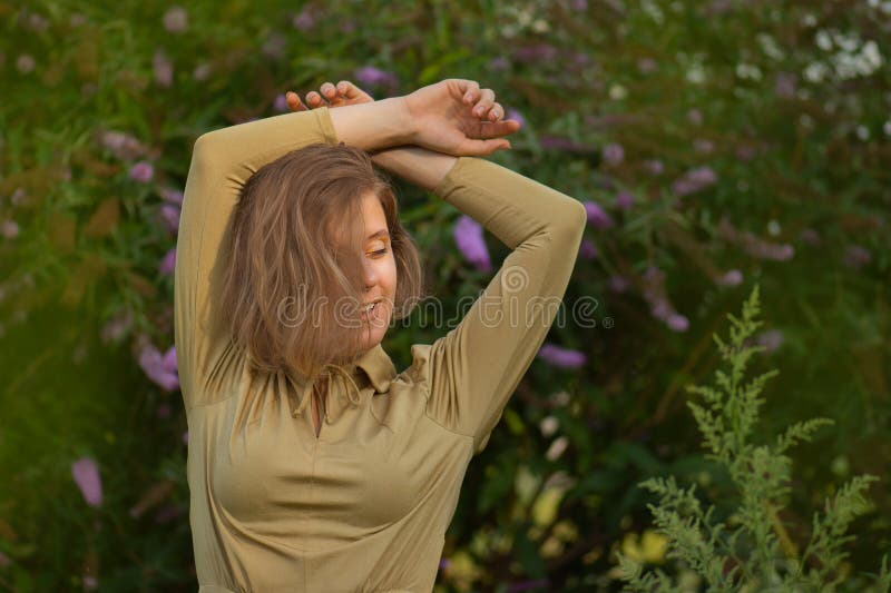 Elegante jonge vrouw in een bloemveld in boeddleia. dame in elegant vintage golden jurk in sunset royalty-vrije stock fotografie Elegante jonge vrouw in een bloemveld in boeddleia. dame in elegant vintage golden jurk in sunset royalty-vrije stock fotografie