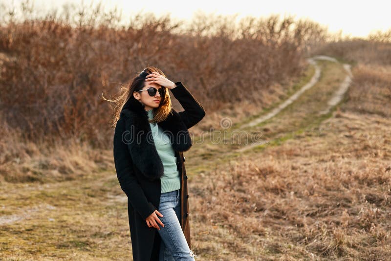 Elegante modelo de moda en estilizadas gafas de sol y abrigo, una hermosa joven mujer Toma exterior imágenes de archivo libres de regalías Elegante modelo de moda en estilizadas gafas de sol y abrigo, una hermosa joven mujer Toma exterior imágenes de archivo libres de regalías
