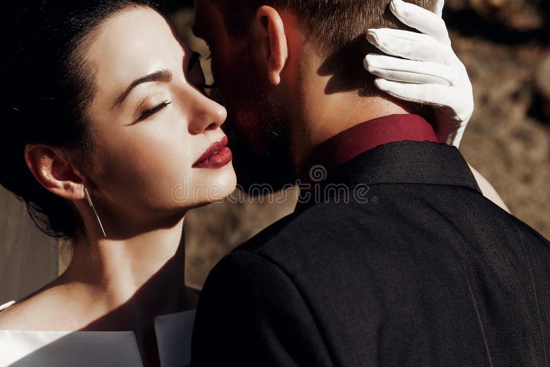 Elegante schitterende bruid die modieuze bruidegom in zonlicht met Ha koesteren royalty-vrije stock foto's Elegante schitterende bruid die modieuze bruidegom in zonlicht met Ha koesteren royalty-vrije stock foto's