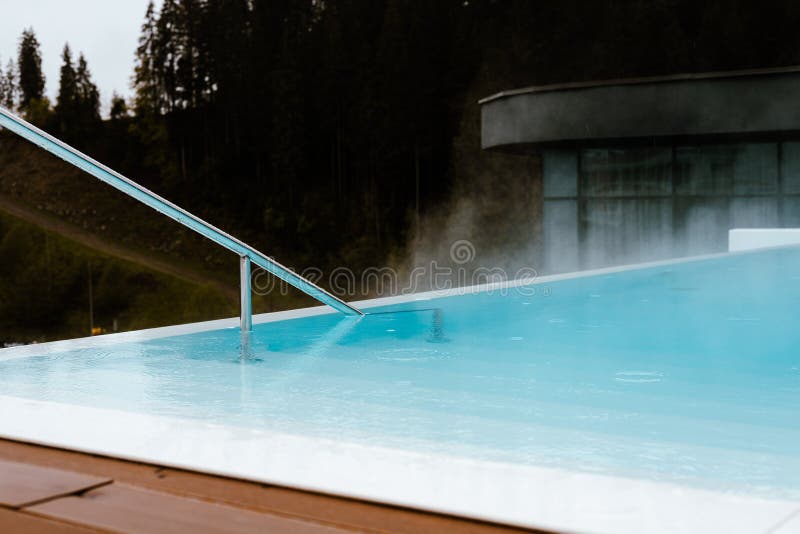 Eleganter Außenpool inmitten der Natur perfekt für einen erholsamen Urlaub Ein ruhiges Wasser mit Dampfaufgang stockbilder