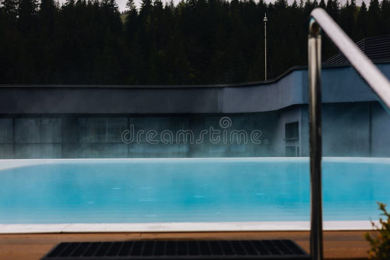 Eleganter Außenpool inmitten der Natur perfekt für einen erholsamen Urlaub Ein ruhiges Wasser mit Dampfaufgang stockbild