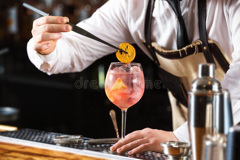 Eleganter Kellner macht das rosa Cocktail, das orange Chips hält stockbild Eleganter Kellner macht das rosa Cocktail, das orange Chips hält stockbild