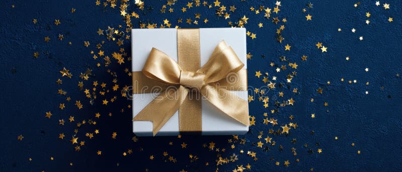 The elegantly wrapped gift box adorned with a golden bow and star confetti. image royalty free stock photo.
