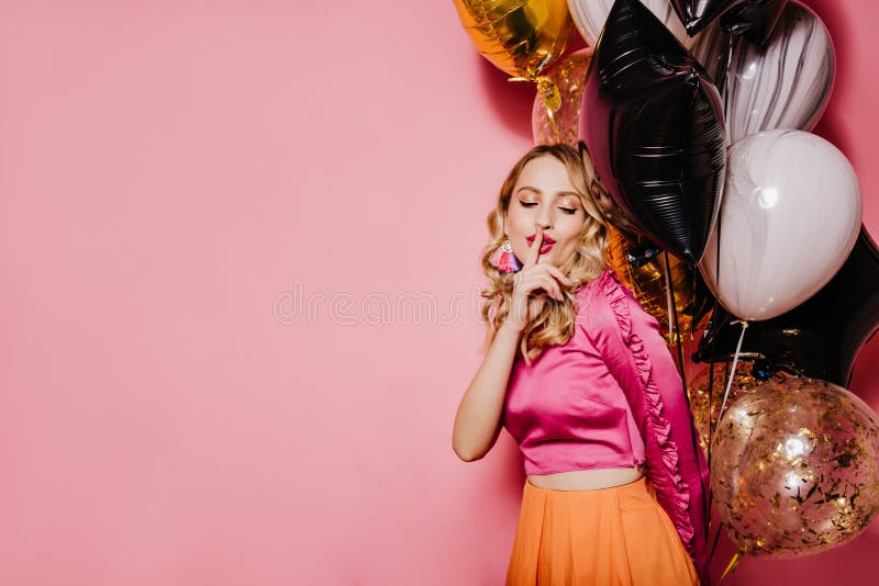 Elegantă fată de aniversare care pozează pe fond roz. Fotografie de interior a unei femei cu părul frumos și cu baloane de petrece royalty free stock photos