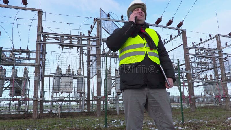 Elektrikeringenieur, der intelligentes Telefon nahe Nebenstelle im Winter geht und verwendet stock video footage