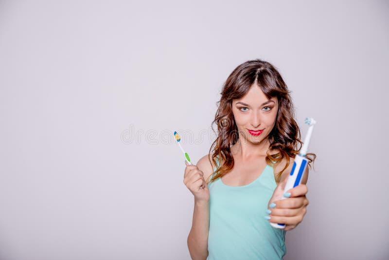 Elektrische und traditionelle Zahnbürste Hygiene der Mundhöhle Eine junge Schönheit wählt zwischen einem elektrischen und lizenzfreie stockfotos Elektrische und traditionelle Zahnbürste Hygiene der Mundhöhle Eine junge Schönheit wählt zwischen einem elektrischen und lizenzfreie stockfotos