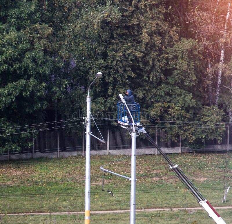 Elektryk zmienia lampę na lekkim słupie wierza dźwignięcia pracownik słup zamieniać żarówkę fotografia royalty free Elektryk zmienia lampę na lekkim słupie wierza dźwignięcia pracownik słup zamieniać żarówkę fotografia royalty free