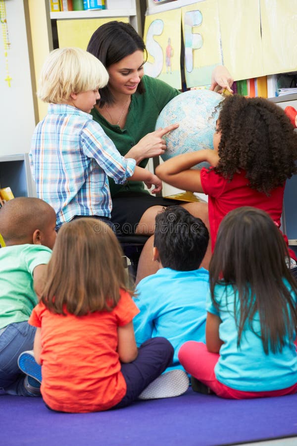 Elementary Pupils In Geography Class With Teacher Sitting Down Listening