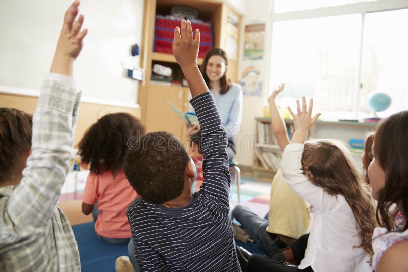 Elementary school kids raising hands to teacher, back view. Happy multiethnic boys stock images, royalty-free photos and pictures