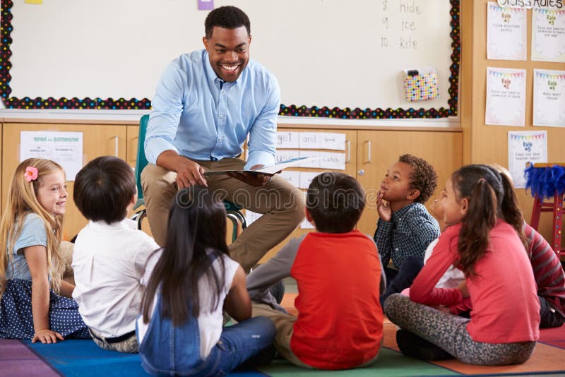 Elementary school kids sitting around teacher in a classroom