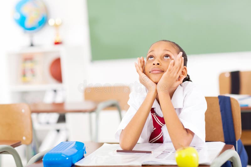 Young elementary schoolgirl daydreaming in classroom