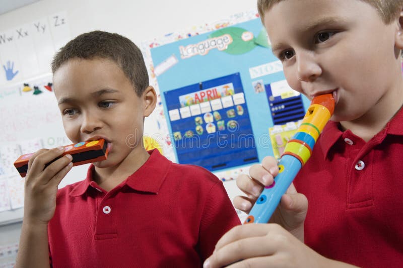 Elementary school boys playing musical instrument in class. Elementary school boys playing musical instrument in class