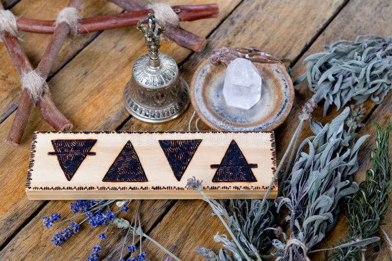 The Elements - Earth, Fire, Water, Air with brass bell, quartz crystal, branch pentagram and bundles of dried herbs on wooden background