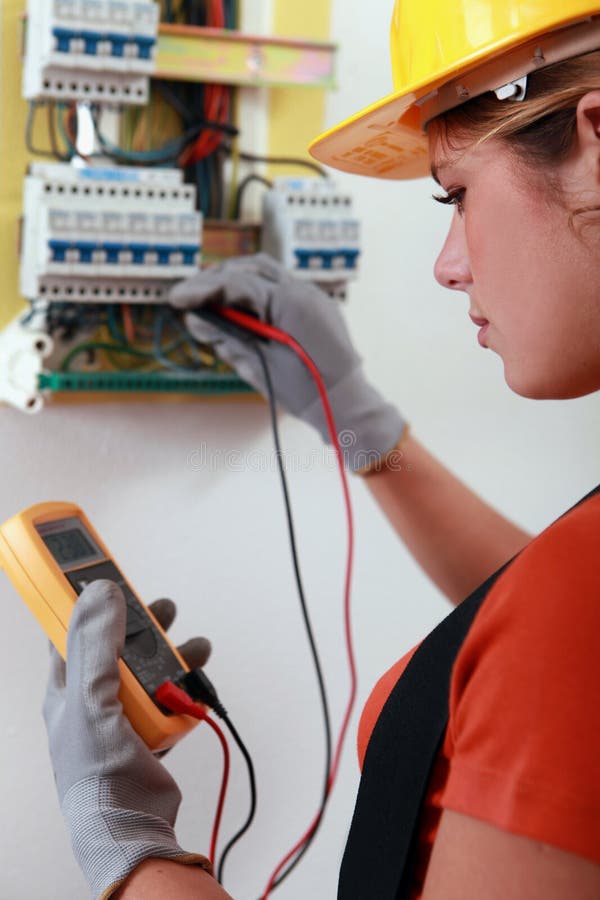 Elettricista femminile che controlla fusebox immagine stock Elettricista femminile che controlla fusebox immagine stock