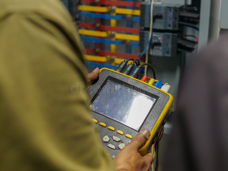 Elettricista. L'ingegnere elettronico utilizza un multimetro per testare l'impianto elettrico e la corrente di una linea elettrica in un armadio di controllo del sistema elettrico.