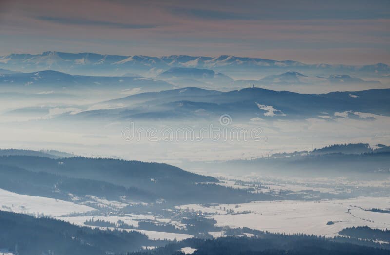 Slnečná zimná scenéria s modrými hrebeňmi a zahmlenými dolinami Slovensko