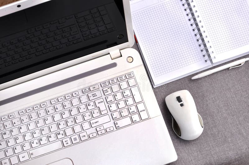 Elevação acima da vista do local de trabalho do escritório com fim do portátil acima do teclado e do rato de computador com cader foto de stock Elevação acima da vista do local de trabalho do escritório com fim do portátil acima do teclado e do rato de computador com cader foto de stock