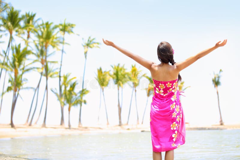 Praising happy freedom woman on beach wearing sarong stretching arms up, enjoying sun in worship and meditation zen. Serene girl seen from backside on Big Island, Hawaii, USA. Praising happy freedom woman on beach wearing sarong stretching arms up, enjoying sun in worship and meditation zen. Serene girl seen from backside on Big Island, Hawaii, USA.