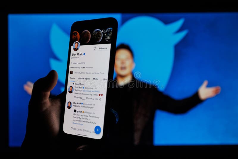 Elon Musk twitter account on mobile phone screen. Twitter logo in background