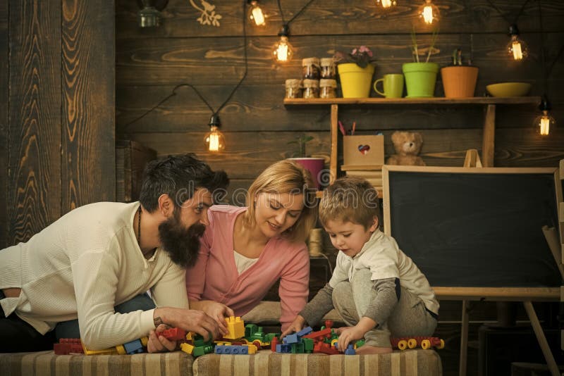 Eltern lehnen sich vorwärts zu ihrem Kind auf Sofa Familienspiel mit Baublöcken Vati, der seinen beschäftigten Sohn betrachtet lizenzfreie stockfotos Eltern lehnen sich vorwärts zu ihrem Kind auf Sofa Familienspiel mit Baublöcken Vati, der seinen beschäftigten Sohn betrachtet lizenzfreie stockfotos