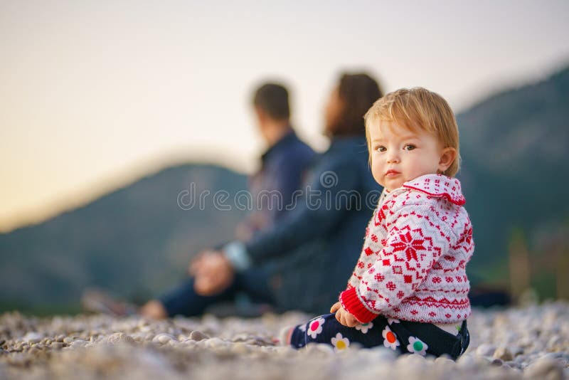 Eltern und Tochter am Winterstrand. Familie in der Natur im Winter. Die Frau und der Mann sind ein Kind in einem Pullover verschwo lizenzfreies stockbild