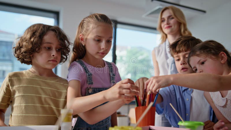 Elèves étudiant cours d'art prendre des crayons colorés closeup. Enfants de groupe banque de vidéos