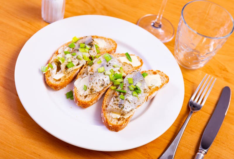 On top of greased bread is slices of lightly salted herring. Sandwiches with butter and fish, decorated with ring of green onion. On top of greased bread is slices of lightly salted herring. Sandwiches with butter and fish, decorated with ring of green onion