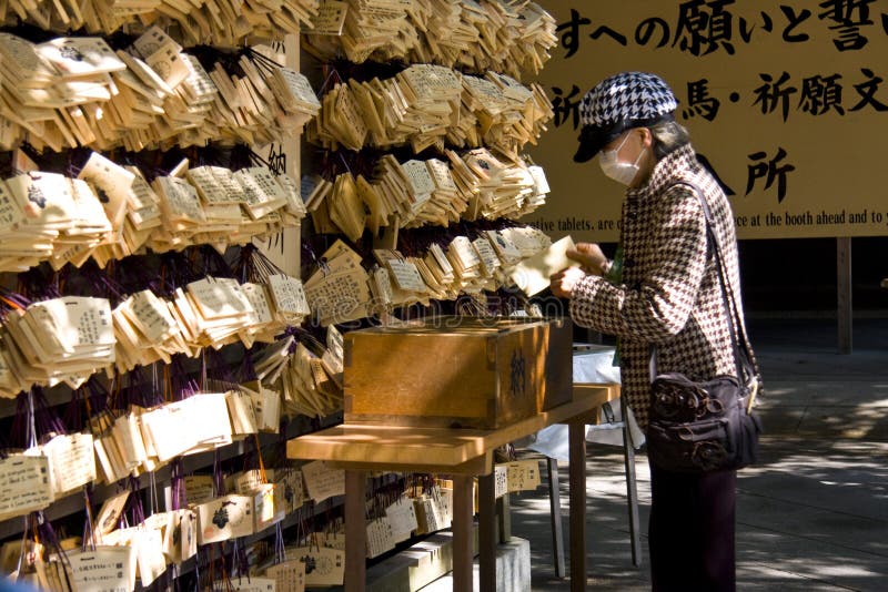 Japanese woman with mask praying in Meiji Jingu shrine. Japanese woman with mask praying in Meiji Jingu shrine.