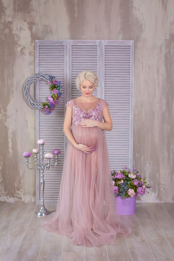 Embarazo, maternidad y concepto futuro feliz de la madre - mujer embarazada en vestido violeta airoso con las flores del ramo con foto de archivo libre de regalías Embarazo, maternidad y concepto futuro feliz de la madre - mujer embarazada en vestido violeta airoso con las flores del ramo con foto de archivo libre de regalías
