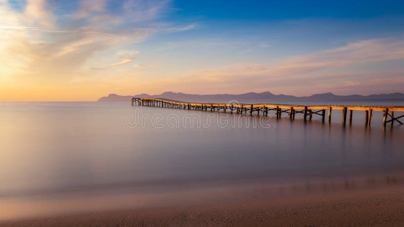 Embarcadero/embarcadero de madera, playa de Muro, Alcudia, salida del sol, montañas, playa aislada, luz del sol de oro, reflexión foto de archivo libre de regalías Embarcadero/embarcadero de madera, playa de Muro, Alcudia, salida del sol, montañas, playa aislada, luz del sol de oro, reflexión foto de archivo libre de regalías