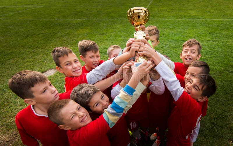 Embroma el fútbol del fútbol - jugadores de los niños que celebran con un trop fotografía de archivo
