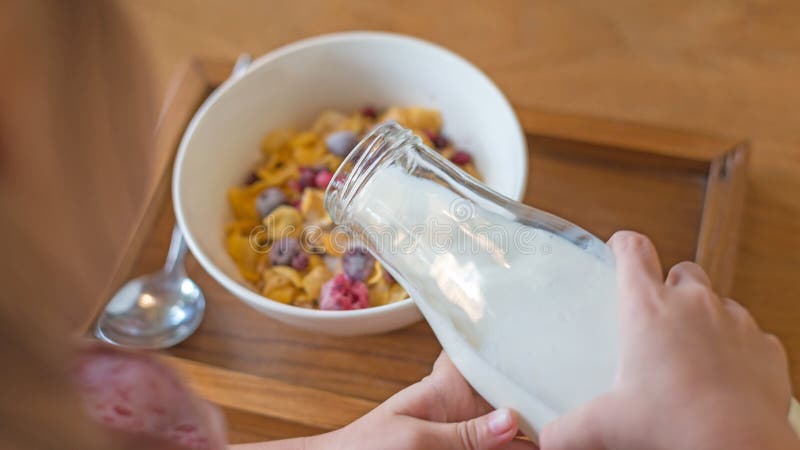 Embrome la mano que vierte la leche fresca en la taza blanca, cereal de los copos de maíz, fotos de archivo libres de regalías Embrome la mano que vierte la leche fresca en la taza blanca, cereal de los copos de maíz, fotos de archivo libres de regalías