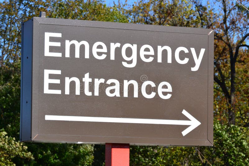 An illuminated sign pointing to the emergency entrance of a hospital. An illuminated sign pointing to the emergency entrance of a hospital
