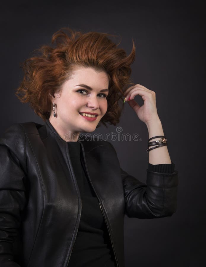 Emocjonalna brunetka pozuje w studiu w rzemiennej pelerynie zdjęcie stock Emocjonalna brunetka pozuje w studiu w rzemiennej pelerynie zdjęcie stock