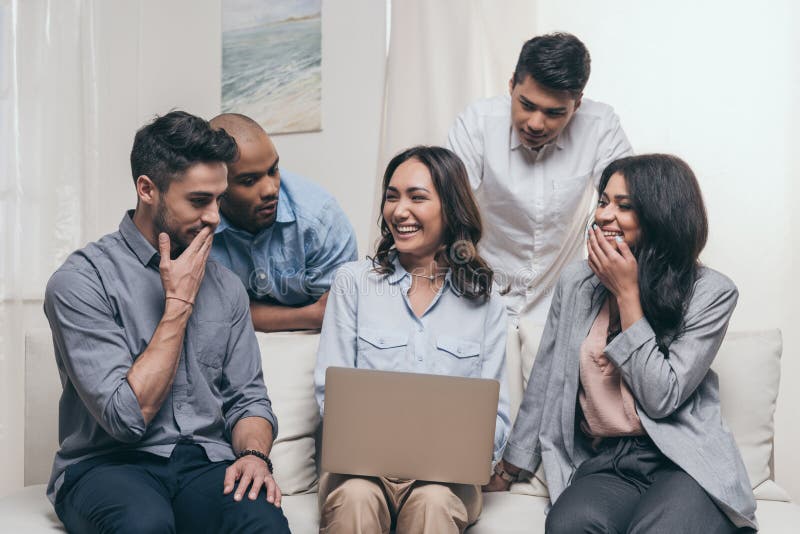 Emocjonalni przyjaciele używa laptop podczas gdy siedzący na kanapie w domu zdjęcie stock Emocjonalni przyjaciele używa laptop podczas gdy siedzący na kanapie w domu zdjęcie stock
