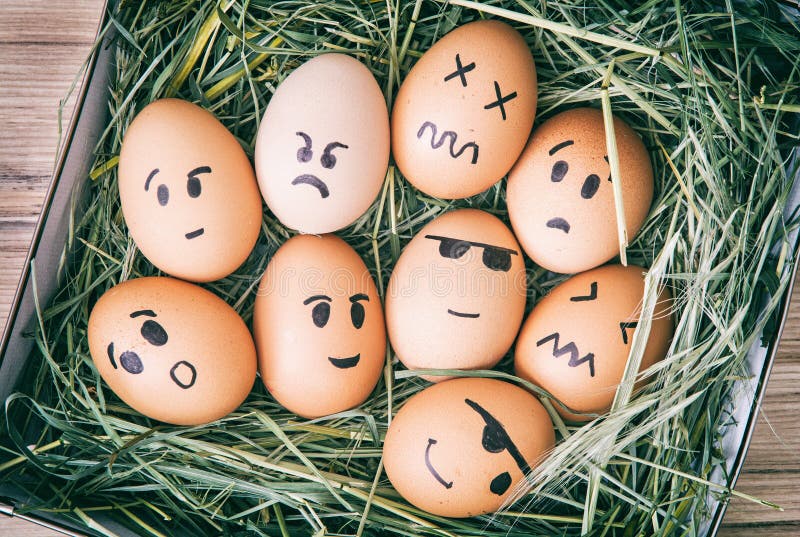 Emotion painted eggs in the box with hay. Funny drawing faces.