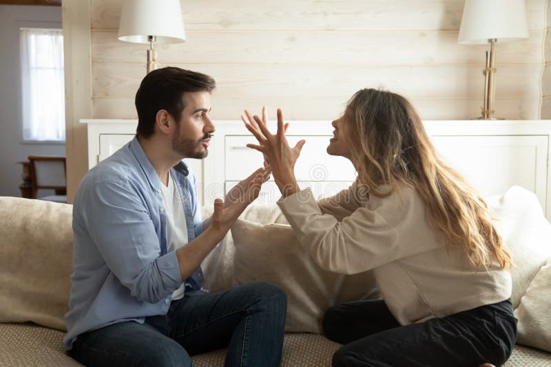 Emotional annoyed stressed couple sitting on couch, arguing at home. Angry irritated nervous women men shouting at each other, figuring out relations, feeling outraged, relationship problems concept. Emotional annoyed stressed couple sitting on couch, arguing at home. Angry irritated nervous women men shouting at each other, figuring out relations, feeling outraged, relationship problems concept.