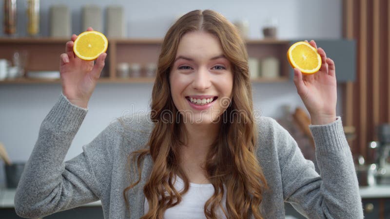 Portrait of cheerful woman having fun with two orange slices at home. Emotional girl making faces with oranges at modern kitchen. Closeup beautiful woman changing emotions with fruit chunk indoors. Portrait of cheerful woman having fun with two orange slices at home. Emotional girl making faces with oranges at modern kitchen. Closeup beautiful woman changing emotions with fruit chunk indoors.