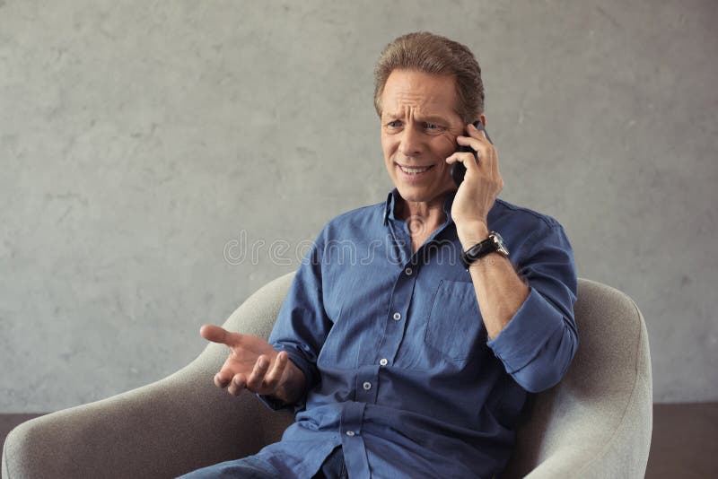 emotional mature man talking on smartphone while sitting stock image emotional mature man talking on smartphone while sitting stock image