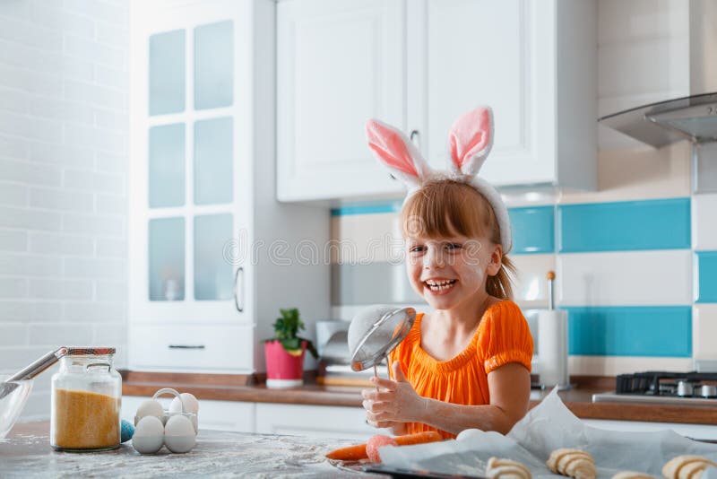 Emotional portrait of cheerful little girl dressed as bunny for Easter While cooking food in kitchen at home. Girl kid