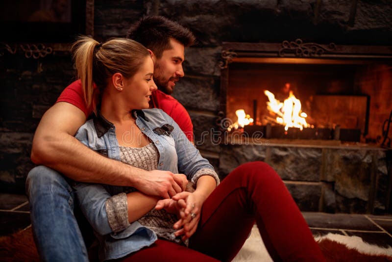 Romantic couple hugging at home front of fireplace. 