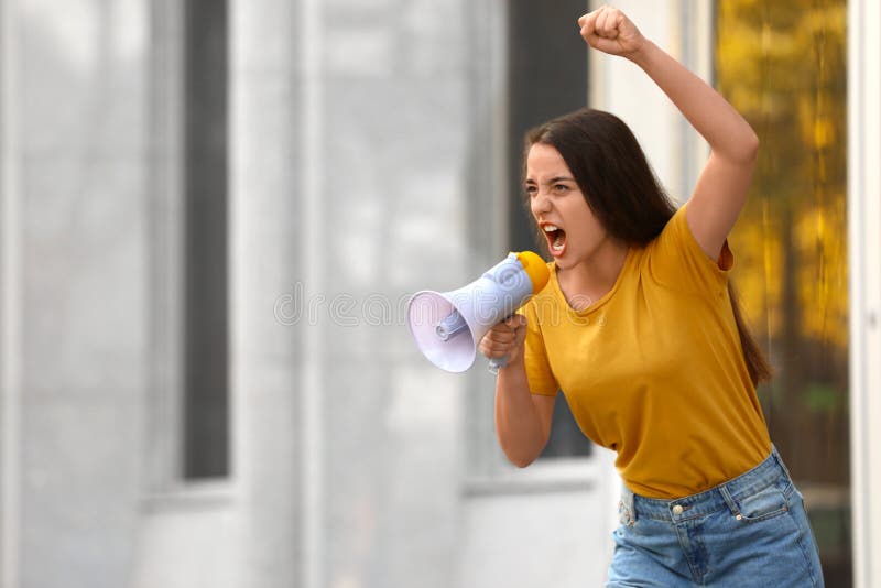 Emotional woman with megaphone outdoors. Protest leader