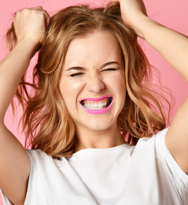 Emotional woman screaming shouting yelling closeup portrait on pink background pull tearing head hair. Female emotions facial expression concept. Emotional woman screaming shouting yelling closeup portrait on pink background pull tearing head hair. Female emotions facial expression concept