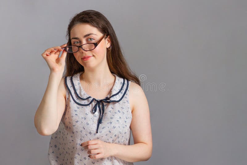 Emotions and people. A beautiful young brunette woman in a blouse, playfully holding the arm of her glasses. Copy space stock image Emotions and people. A beautiful young brunette woman in a blouse, playfully holding the arm of her glasses. Copy space stock image
