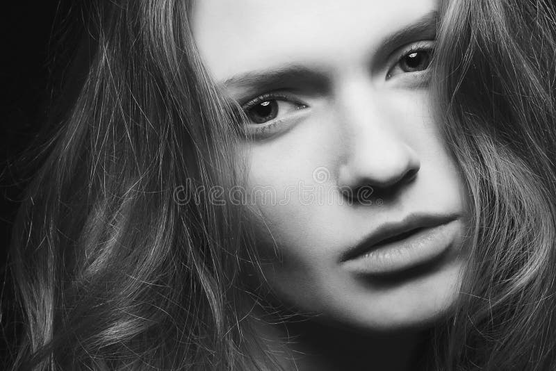 Emotive portrait of a young beautiful girl with curly long hair posing over black background. Perfect skin and hair. Spa salon. stock image Emotive portrait of a young beautiful girl with curly long hair posing over black background. Perfect skin and hair. Spa salon. stock image