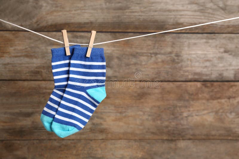 Pair of socks on laundry line against wooden background, space for text. Baby accessories. Pair of socks on laundry line against wooden background, space for text. Baby accessories