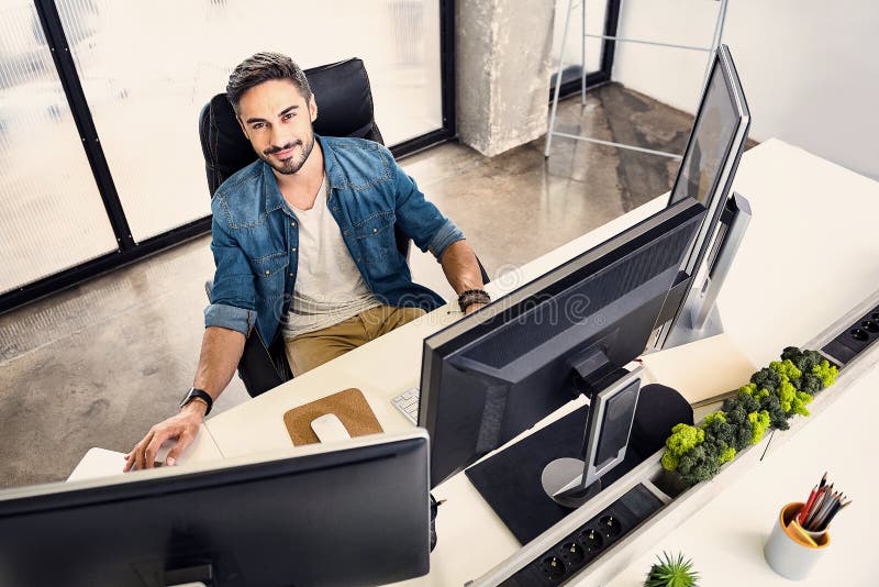 Empleado barbudo sonriente que trabaja en el apartamento cómodo imágenes de archivo libres de regalías Empleado barbudo sonriente que trabaja en el apartamento cómodo imágenes de archivo libres de regalías